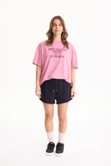Remera de algodón rosada con estampa frontal en tono burdeos con la inscripción "BREAKING NEWS IT'S SUMMER", de manga corta y corte holgado.