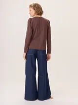 Remera blanca de manga larga con escote en V y detalles de alforzas verticales en el frente y mangas.