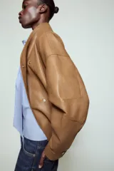 Chaqueta bomber ZW Collection confeccionada en tejido efecto piel de color marrón. Cuenta con cuello subido, manga larga con puño y botón a presión, bolsillos delanteros y bajo recto elástico. Cierre frontal cruzado con botones a presión.