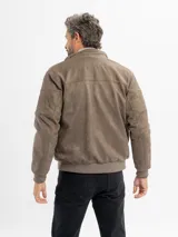 Campera de estilo casual confeccionada en tejido suave con textura tipo gamuza. Presenta cuello alto, cierre frontal, bolsillos laterales y bolsillos frontales con solapa. Incluye detalles de costuras en las mangas y terminaciones elastizadas en puños y cintura.