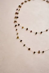 Collar largo de cadena fina dorada con pequeñas piedras naturales engarzadas a lo largo de toda la pieza.