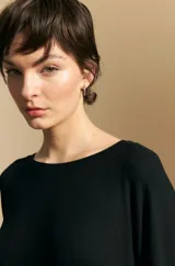 Remera de calce relajado con silueta fluida, confeccionada en tejido de viscosa con elastano. Presenta cuello redondo, mangas cortas y un diseño minimalista de caída suave.