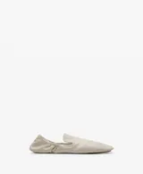 Zapatos tipo ballerinas planas de piel ovina en color blanco, con punta redonda, diseño sin cordones y detalle de fruncido elástico en el talón.