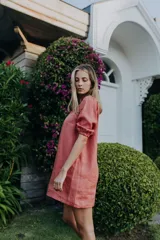 Vestido corto de lino color rosado, con mangas cortas abullonadas con elástico en los puños y corte recto holgado.