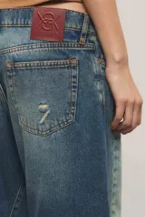 Jeans de tiro bajo confeccionados en denim 100% algodón, con diseño de pierna curva y sutiles desgastes en tono azul vintage.