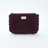 Neceser rectangular de terciopelo color bordó, con detalle de volados en los bordes y cierre superior. Incluye una etiqueta decorativa con la inscripción Beauty Club Collection.