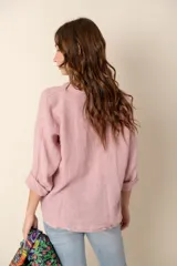 Camisa de lino color rosado, de corte holgado y cuello mao, con mangas 3/4 y cierre frontal con botones. 