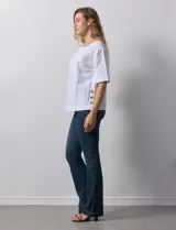 Blusa blanca de algodón, manga corta amplia, con escote redondo y detalle de botones en los tajos laterales del ruedo.