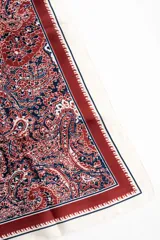 Bandana cuadrada con estampado paisley en tonos bordó, azul marino y blanco, con bordes en tono crudo y marco decorativo.