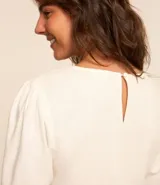 Blusa de viscolino color amarillo pálido, con cuello redondo y mangas cortas abullonadas.