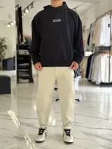 Canguro oversize color beige, con capucha y amplio estampado tipográfico en la espalda.