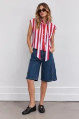 Blusa sin mangas a rayas verticales rojas y celestes, con cuello camisero y tiras frontales para anudar.