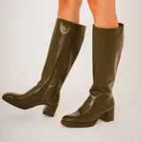 Botas altas de cuero color negro con diseño texturizado estilo animal print tipo cocodrilo en la parte frontal y trasera, taco cuadrado y puntera cuadrada.