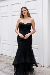 Vestido largo negro strapless tipo corset con tul y lentejuelas, de corte sirena y falda con volados.