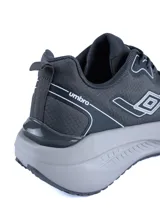 Championes deportivos Umbro modelo Spin Lock, color negro con detalles en verde azulado. Presentan un diseño aerodinámico con malla transpirable, refuerzos sintéticos y una suela de plataforma blanca con amortiguación.