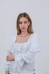 Blusa blanca con bordado inglés, escote cuadrado, mangas largas abullonadas con volados y cierre frontal con botones.