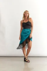 Minifalda cruzada color turquesa de seda con flecos negros en el borde.