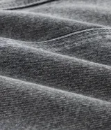 Campera de jean gris con efecto desteñido, corte oversized, cuello inglés, cierre frontal con botones niquelados y aplicaciones de brillos y piedras en la parte superior delantera.