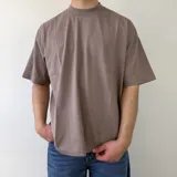 Remera boxy de color marrón topo, de manga corta, con diseño estampado en la espalda de tres flores estilizadas en color blanco.