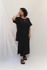 Falda larga de estilo deportivo confeccionada en tejido de algodón y poliéster. Presenta cintura elástica con cordón de ajuste en color fucsia, bolsillos laterales y un aplique decorativo de acrílico en la parte frontal.