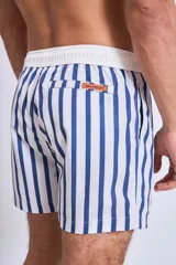 Short de baño con estampado botánico en tonos tierra, rosados y verdes. Presenta cintura elástica con cordón ajustable y un pequeño parche con logo en el ruedo.