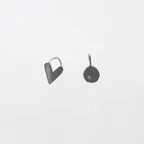 Par de aros asimétricos de plata, uno con forma de corazón y otro con forma circular con la letra S grabada.