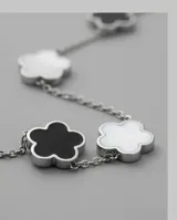 Collar de cadena de acero con cinco dijes en forma de flor, alternando detalles en nácar blanco y ónix negro.