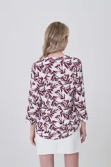 Camisa de viscosa con estampado botánico en tonos bordó sobre fondo blanco, cuello mao y cierre frontal con botones. Presenta bolsillos frontales y mangas tres cuartos.