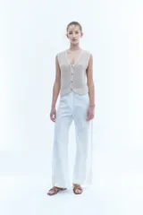 Pantalón blanco de lino de corte recto y pierna ancha, con detalle de puntilla en los laterales.