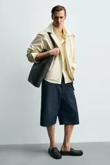 Mocasín destalonado de cuero negro con detalle de antifaz en el empeine, puntera cuadrada y suela plana con pequeño tacón.