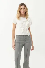 Remera blanca de algodón con cuello redondo y mangas cortas. Presenta volados verticales en el frente.