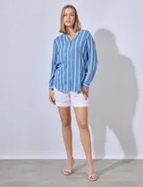 Camisa celeste con rayas verticales blancas, de corte clásico, cuello a la base, escote en V y cierre frontal con botones.