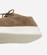 Zapato estilo moc toe para hombre, confeccionado en poliuretano con acabado aterciopelado en color marrón, cierre de cordones y suela gruesa de EVA en color blanco.