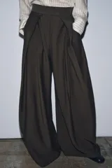 Pantalón de tiro medio color beige perteneciente a la colección ZW Collection, de corte ancho y recto, con detalle de pliegues frontales y cierre con cremallera y ganchos metálicos.