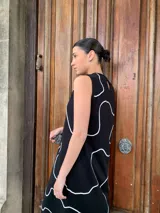 Vestido midi negro con estampado de líneas blancas, sin mangas y cuello redondo.