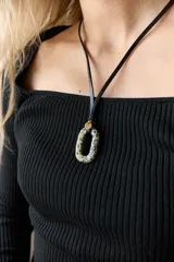 Gargantilla de tiento de cuero negro con dije colgante de piedra natural ovalada y argolla metálica dorada.