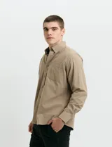 Camisa de franela lisa con cuello button-down, manga larga, botones al tono y bolsillo frontal en el pecho.