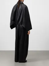 Pantalón negro de piel ovina, tiro alto con cintura cruzada y pinzas delanteras. Presenta volumen en la parte delantera izquierda y pierna ancha con corte horizontal a la altura de la rodilla.