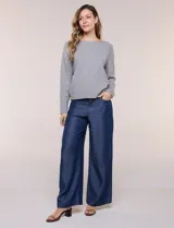 Buzo de punto fino color gris, de calce relajado, escote redondo amplio y canesú con textura acanalada. Cuenta con apliques de tachas metálicas doradas en la línea del hombro, mangas largas de hombro caído y puños y ruedo acanalados.