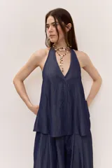 Blusa azul de denim liviano, con escote en V y cuello halter. Cuenta con cierre frontal de botones y diseño suelto de caída fluida.