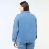 Blusa recta de jean azul claro, con cuello camisero, escote en V con abertura y un bolsillo aplicado en el pecho.