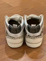 Zapatillas urbanas de media caña, con estampado de piel de pitón en tonos grises y detalles en cuero color crema. Presentan una estrella dorada en el lateral, puntera perforada y cuello acolchado plateado. Suela de goma con efecto envejecido.