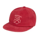 Gorra de visera color rojo con bordado frontal que incluye el logo floral y la palabra 'Rhythm'.