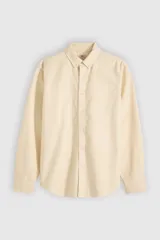 Camisa de manga larga color amarillo claro con cierre frontal de botones, cuello camisero y calce clásico.