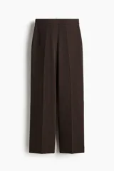 Pantalón sastrero de tiro alto y piernas amplias, color marrón, con pliegues frontales y traseros.