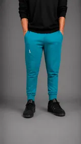 Pantalón tipo jogger color turquesa, con cintura elástica, bolsillos laterales y puños acanalados en los tobillos. Presenta un pequeño logo bordado en la pierna derecha.