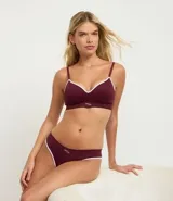 Bombacha tipo bikini de corte clásico, confeccionada en tejido de poliamida texturizado con tecnología seamless. Presenta un diseño liso en color bordó con bordes en contraste color blanco y detalle de logo bordado en el frente.