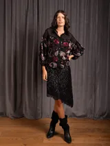 Pollera corta negra de lentejuelas miniatura, con corte asimétrico y detalle de encaje en el bajo.