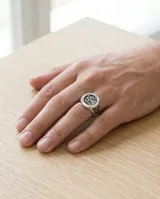 Anillo de acero con diseño circular grabado que representa a San Cristóbal, santo patrono de los viajeros, con detalles en relieve en los laterales.