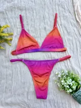 Conjunto de bikini con corpiño triangular fijo y bombacha colaless regulable, con estampado degradado en tonos naranja, rosado y violeta.